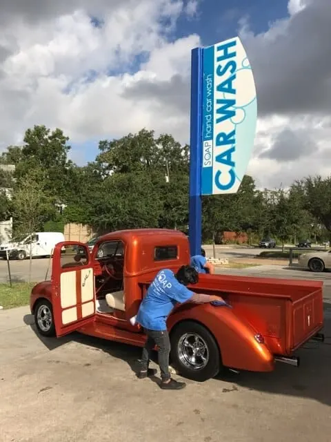 Classic orange pickup truck being hand washed