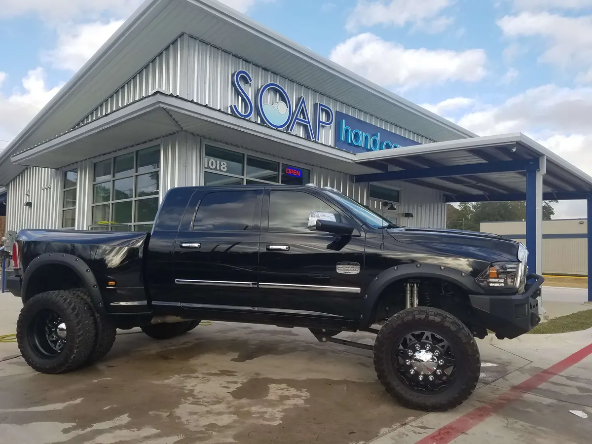 Lifted black pickup truck with custom wheels outside SOAP Hand Car Wash
