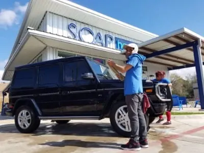 SOAP crew drying a black Mercedes G-Wagon after a hand wash