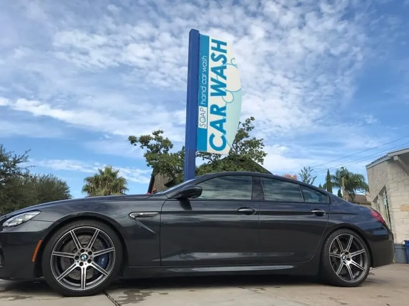 Gray BMW M6 Gran Coupe under a SOAP car wash sign