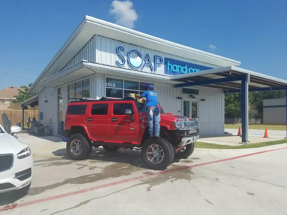 Crew member hand washing a red Hummer H2 at SOAP
