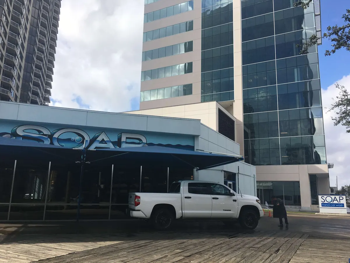 White pickup truck being washed at a SOAP location among Houston office towers