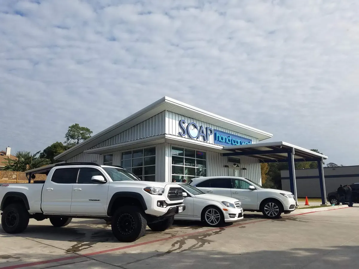 White pickup truck and SUV parked outside a SOAP Hand Car Wash building
